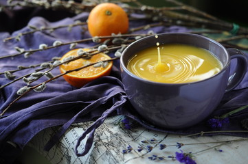purple ceramic cup of orange juice with splash and drops close-up 