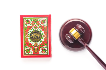 Flatlay picture of Quran with law gavel on white background for sharia or Islamic law concept. Large Arabic word mention the Holy Quran is with variance recitation and correct pronounciations method. - obrazy, fototapety, plakaty