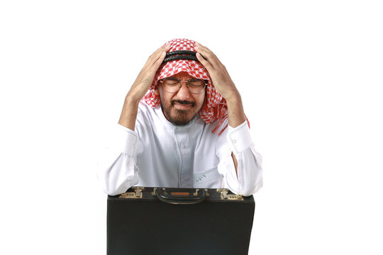 Arab man portrait wearing keffiyeh with a black briefcase, put his head in his hands, suffering from migraine headache isolated on white background.