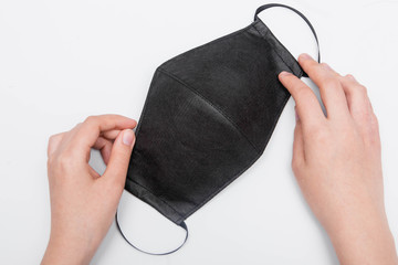 First-person view, close-up of hands holding a handmade black face mask, isolated on white background. Medical masks deficiency concept.
