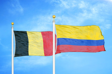 Belgium and Colombia two flags on flagpoles and blue cloudy sky