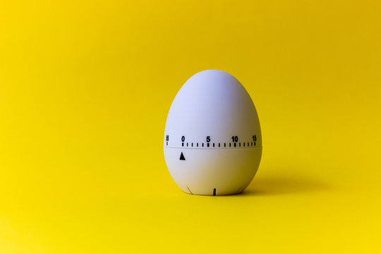 White Egg Timer On Yellow Background. Happy Easter In The Kitchen. Home Related, Home Staying. Free Copy Space.