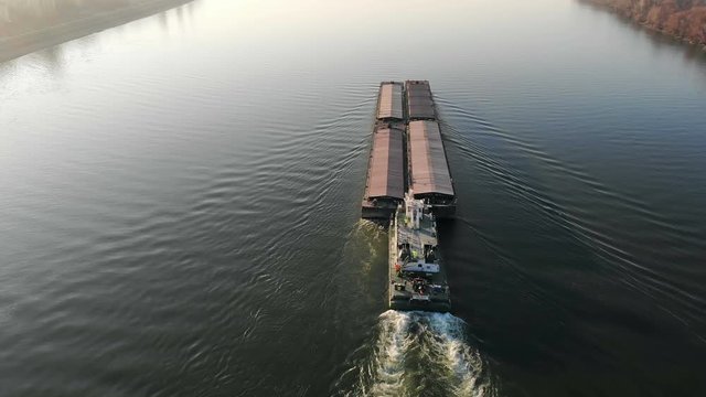 Drone video of tugboat pushing a barge on the river
