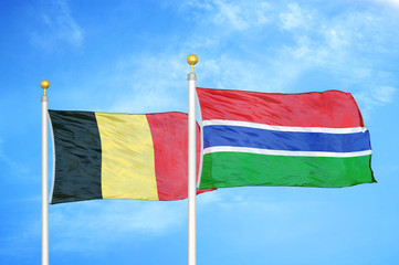 Belgium and Gambia two flags on flagpoles and blue cloudy sky