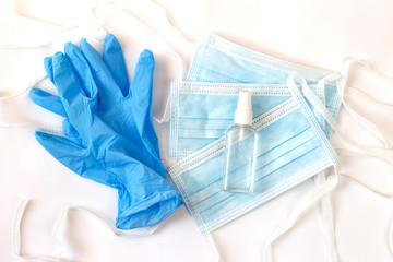 A pair of thin blue medical latex gloves, a protective mask and an antibacterial spray on a white background. Disposable rubber medical gloves and mask. Protective items. Funds.