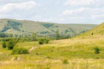 Fototapeta na wymiar valley, meadow between hills with dirt country road