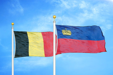 Belgium and Liechtenstein two flags on flagpoles and blue cloudy sky