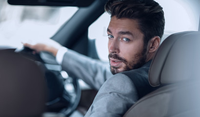 Fototapeta na wymiar Successful man sitting behind the wheel of a prestigious car