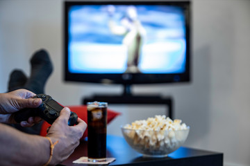 man playing game with foot over the table with popcorn and soda