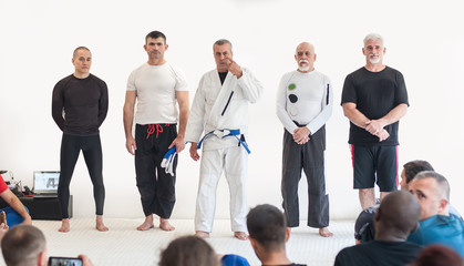 Respected, reputable and experienced head martial arts sensei master with international multiethnic group of his instructors, addresses his students on kapap seminar in dojo gym. Front view