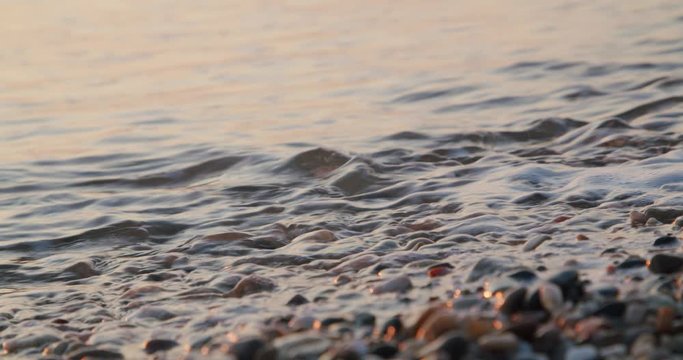 Real time extreme close up shot shoreline, ocean over pebbles in Almeria, Spain