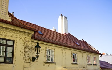A house with a white chimney on the roof and a lantern hanging on the wall (Prague, Czech Republic, Europe)