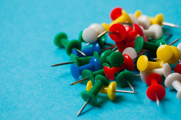 Multicolored push pins on a blue background macro closeup