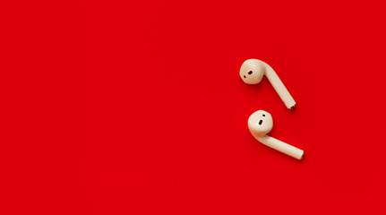 close-up of wireless white headphones on a red background