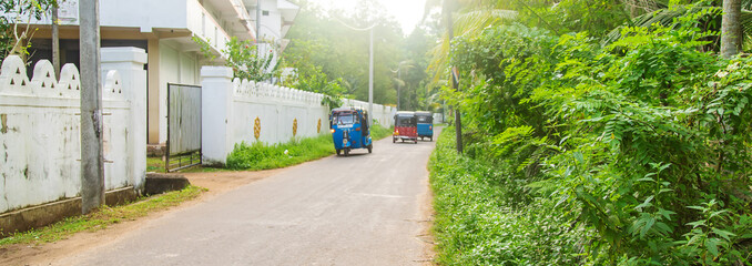 Tuk tuks ride along the road. Sri Lanka. Selective focus.