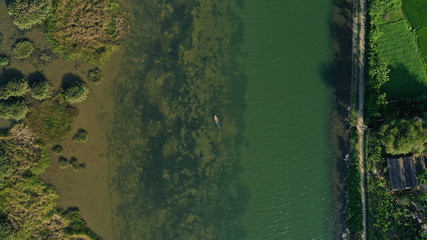 Aerial top down view of Thu Bon river with small round islets covered by green jungle grass on water. Long Tail boat is floating on river. Beautiful landscape from drone.