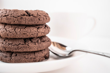 Four chocolate chip cookies on a white saucer