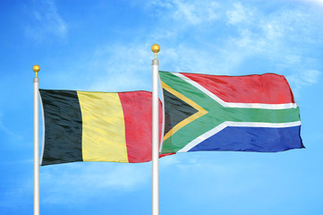 Belgium and South Africa two flags on flagpoles and blue cloudy sky