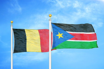 Belgium and South Sudan two flags on flagpoles and blue cloudy sky