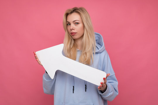 A beautiful young blonde holds a white arrow pointing up. Concept of economic growth