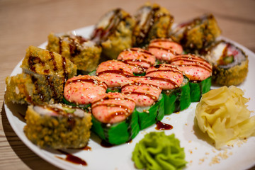 Hot baked set of rolls on a white plate with wasabi and ginger