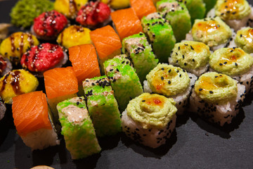 Set of rolls on a black plate with wasabi and ginger