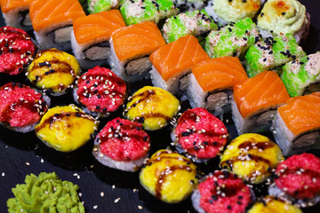 Set of rolls on a black plate with wasabi and ginger