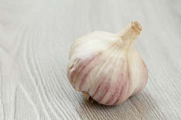 Raw unpeeled garlic bulb on a gray wooden background.