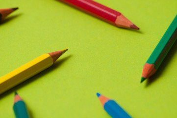 Pencils of different colors on green design paper