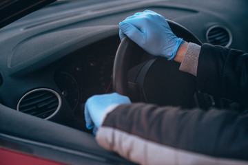 A man holds the steering wheel of a car in protective medical gloves. Hands close-up. Safe drive in a taxi during pandemic coronavirus. Protect driver and passengers from bacteria and virus infection