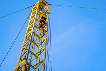 Wireline equipment hanging from top drive ready to be lowered downhole for logging. An oil well engineer works from the back of specialised van to log the condition of steel casing inside an oil well.