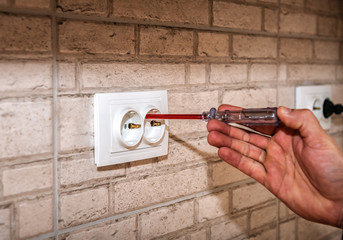 the electrician checks the voltage in the socket