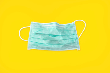 antiviral medical mask for protection against coronavirus. prevention of the spread of virus and pandemic COVID-19.on yellow background and clipping path for using. top view