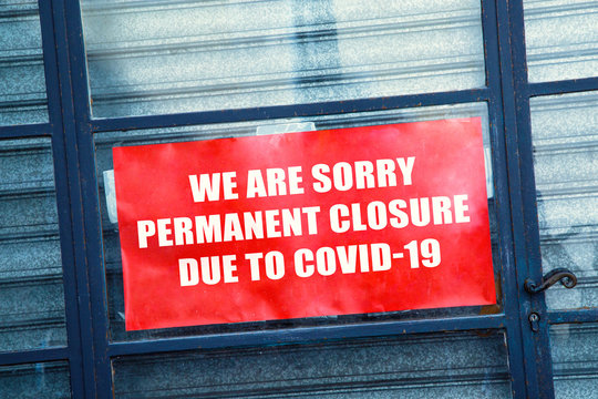 Red closed sign in the window of a shop displaying permanent closure