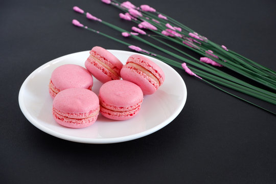 Macaroons and flowers on a black background. Sweets