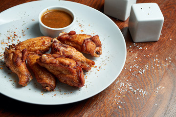Great beer snack - spicy baked buffalo wings. BBQ wings with garnish of french fries on a wooden tray. Top view, food flat lay. Pub food