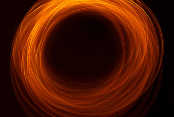 Vibrant neon gold color in abstract swirls on a black background. Light painting