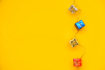 Multicolored little gift boxes on yellow background. Top view. Copy, empty space for text