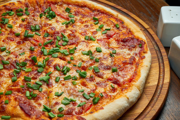 Baked pizza with salami chorizo with red sauce and melted cheese on a wooden background in a composition with ingredients. Close up