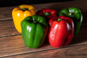 seis ajís morrón de diferentes colores sobre una tabla de madera