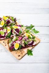 Pickled Marinated Herring and Beetroot Open Sandwich on Rye Bread. Traditional Danish Smorrebrod. Selective focus.