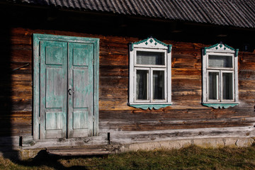 Fototapeta na wymiar Simple authentic wooden village house with windows with shutters and old doors. Belorussian village.