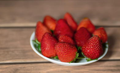 muchas fresas sobre un bol en una madera con desenfoque 