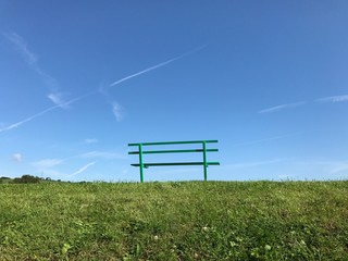 Wooden bench in a public park isolated against deep blue sky. Space for copy