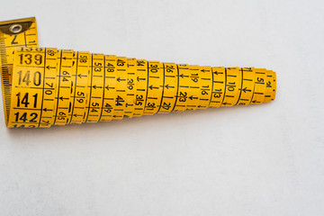 Yellow dressmaker's tape measure for clothing and its derivatives
