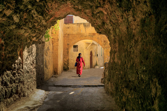 Alte marokkanische Frau geht mit roten Kaftan und Kopftuch durch die Gassen der Altstadt von Marrakesch
