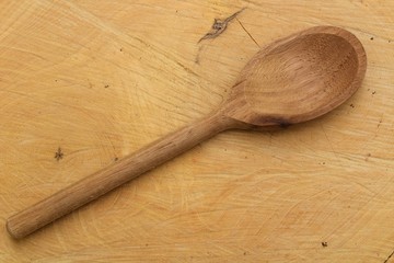 Top view of rustic wooden spoon on a wood plank.