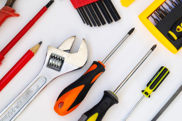 Construction tools lie on a white background. Screwdrivers, a saw, a gas wrench, a pencil, pliers, a screwdriver lie as a pattern.