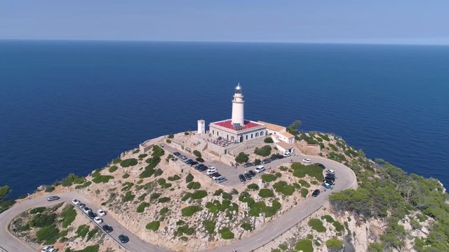 Lighthouse on rocky seashore with curved road
