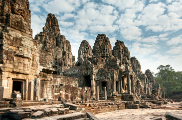 Fototapeta na wymiar Beautiful towers of the 12th century Bayon temple under white clouds, Cambodia. Historical landmark of Angkor. UNESCO world heritage site